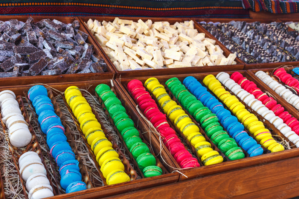 Colorful macaroons. Traditional sweets with silver tongs