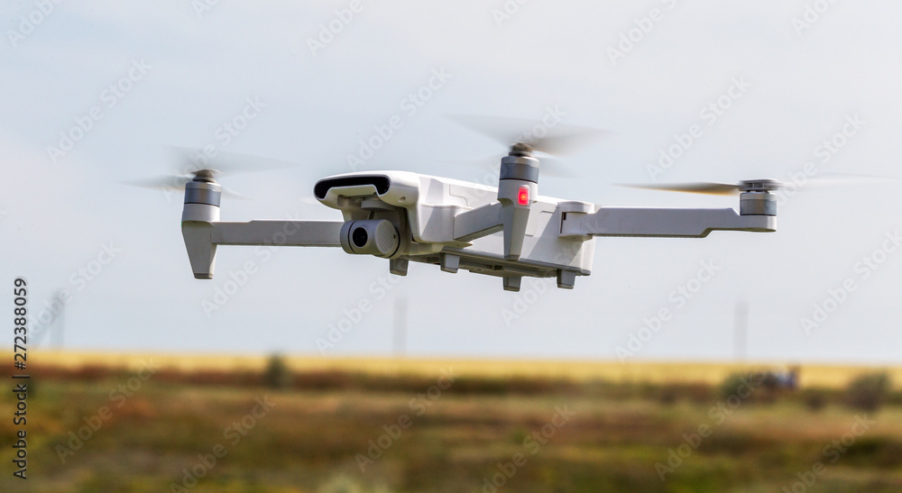 Professional filming drone flies in the air at a low altitude against a blue sky. Drone makes photos. Modern new technology. Ready background with place for your text Professional filming drone flies in the air at a low altitude against a blue sky. Drone makes photos. Modern new technology. Ready background with place for your text
