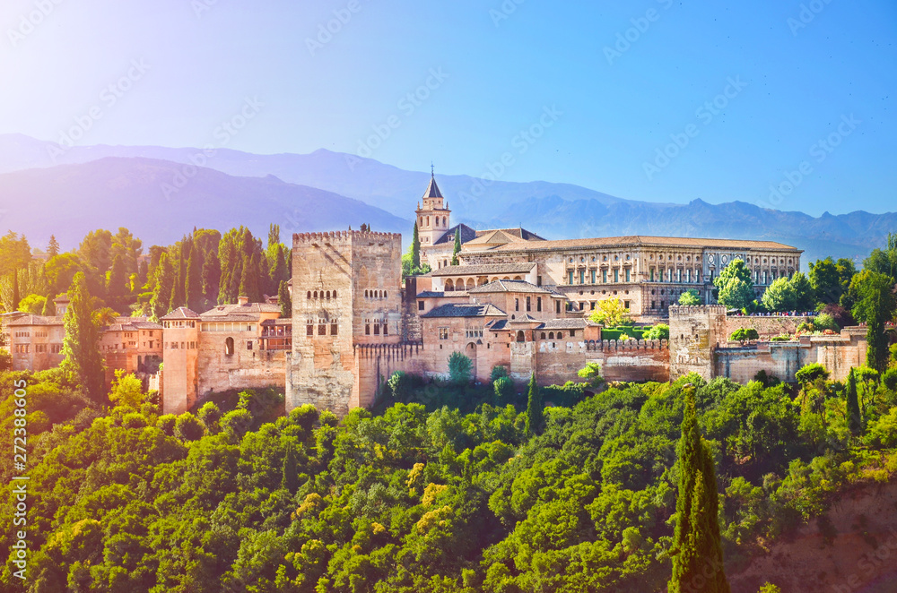Amazing Alhambra palace complex taken in the morning in sunrise light. Beautiful piece of Moorish architecture, surrounded by green trees, is located in Granada, Spain
