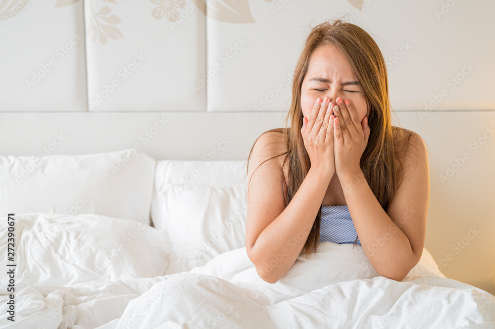 Young sick woman blowing her nose while in bed,Concept background Young sick woman blowing her nose while in bed,Concept background
