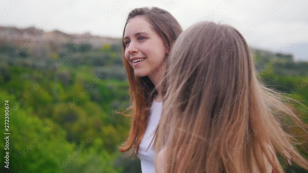 Two young women go and look around. On the background of the landscape Two young women go and look around. On the background of the landscape