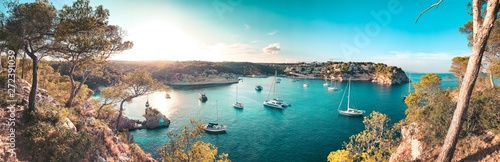 Panorama view of a beach bay with turquoise blue water and sailing boats and yachts at anchor with framed pine trees. Lovely romantic Cala Portals Vells, Mallorca, Spain. Balearic Islands photo