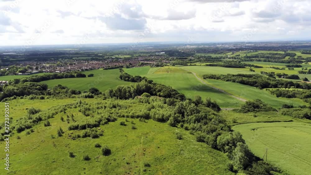 Cloud shadows moving across agricultural farmland meadows & British countryside buildings on the skyline. Right pan aerial. Cloud shadows moving across agricultural farmland meadows & British countryside buildings on the skyline. Right pan aerial.