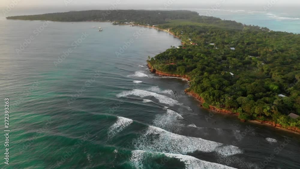 Aerial Pan Down: Waves By Forest Covered Island Surrounded By Bright Blue Ocean - Little Corn Island, Nicaragua Aerial Pan Down: Waves By Forest Covered Island Surrounded By Bright Blue Ocean - Little Corn Island, Nicaragua