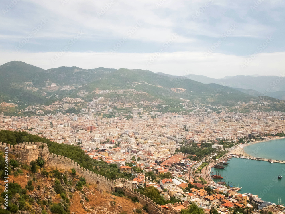 Panoramic view of Alanya, nautical vessels in the harbor, Alanya Castle fortress wall and mountains. Alanya, Antalya, Turkey