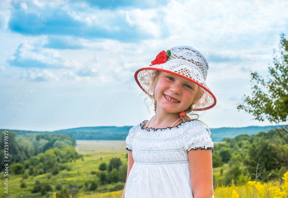 Cute little laughing girl walking in field of summer yellow flowers. Happy childhood