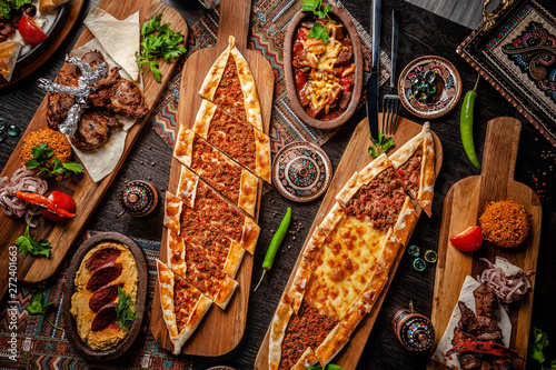 Traditional Turkish cuisine. Pizza, pita, pidesi, sucuk, hummus, kebab, bulgar. Many dishes on the table. Serving dishes in restaurant. Background image. Top view, flat lay photo