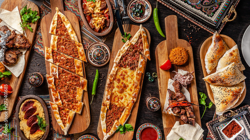Traditional Turkish cuisine. Pizza, pita, pidesi, sucuk, hummus, kebab, bulgar. Many dishes on the table. Serving dishes in restaurant. Background image. Top view, flat lay photo