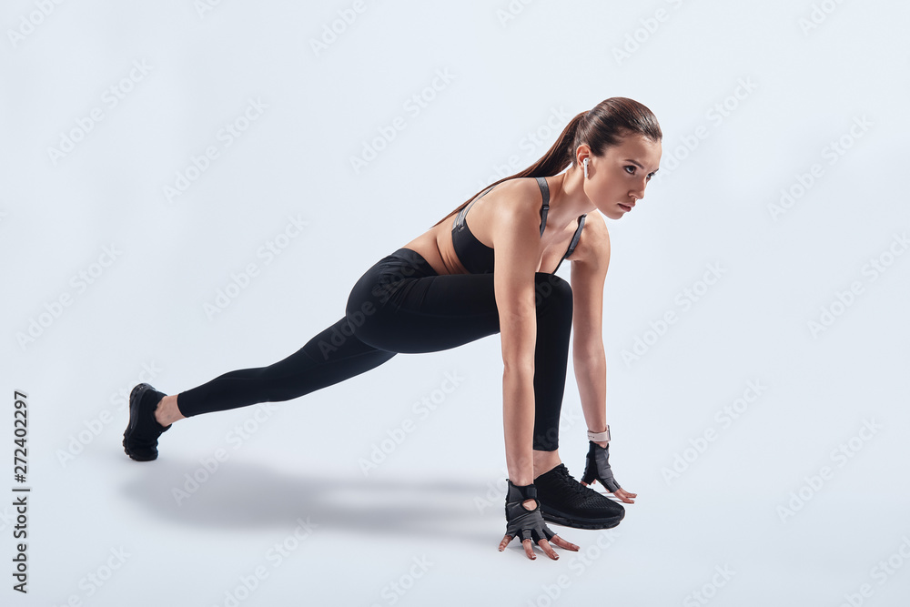 Training for the big day. Attractive young woman stretching while exercising against grey background Training for the big day. Attractive young woman stretching while exercising against grey background