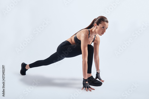 Training for the big day. Attractive young woman stretching while exercising against grey background