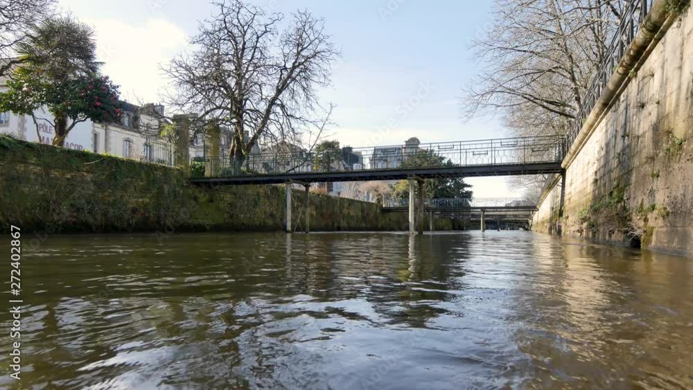 View near the water of the Odet River, in the city of Quimper, in the finistère department, in Brittany, in the west of France. Blue sky, daylight. A bridge is on the background. View near the water of the Odet River, in the city of Quimper, in the finistère department, in Brittany, in the west of France. Blue sky, daylight. A bridge is on the background.