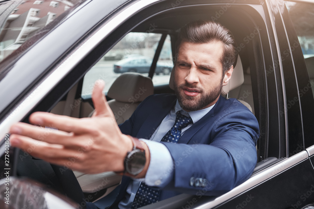 I don't like it. Angry and emotional businessman in formal wear is gesturing and making a grimace while driving his car.