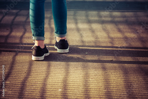 Young girl in jeans and sneakers walking down the street on a summer day.
