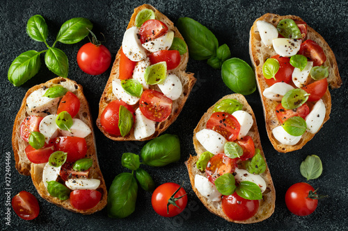 Bruschetta with tomatoes, mozzarella cheese and basil on a cutting board. Traditional italian appetizer or snack, antipasto. Top view with copy space. Flat lay