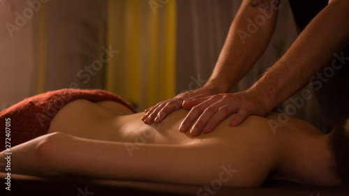 Professional male masseur doing massage for female client at spa salon