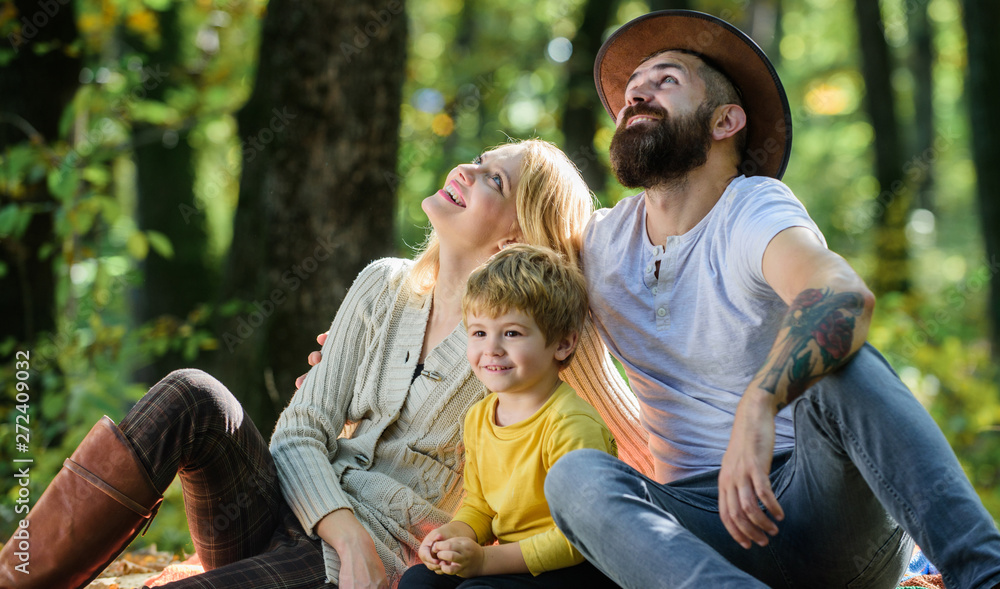 Family day concept. Happy family with kid boy relaxing while hiking in forest. Family weekend. Mother father and little son sit forest picnic. Good day for spring picnic in nature. United with nature Family day concept. Happy family with kid boy relaxing while hiking in forest. Family weekend. Mother father and little son sit forest picnic. Good day for spring picnic in nature. United with nature