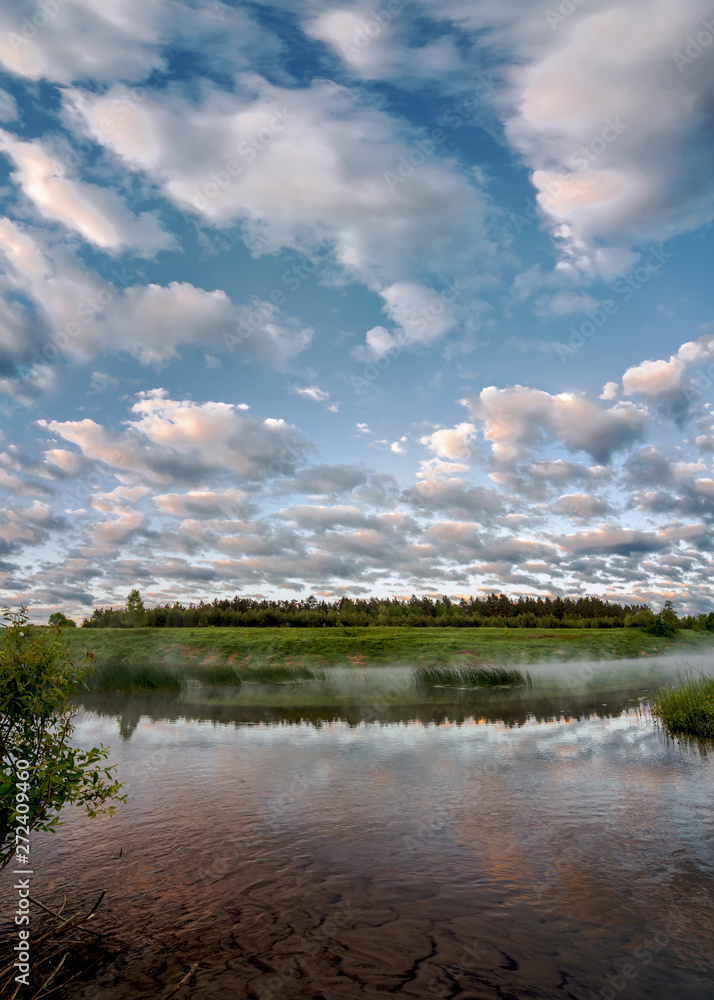 Reflection of clouds in the water. Early morning on the Ugra river