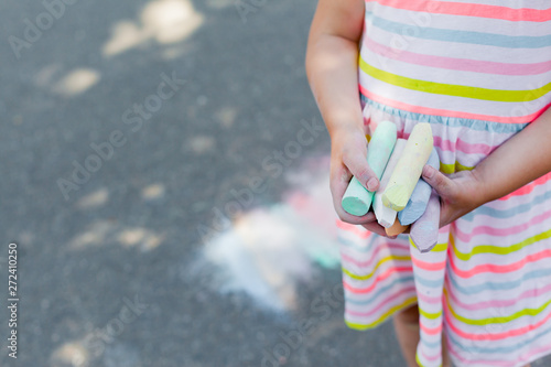 Closeup of child holding colored chalk for drawing. Outdoor entertainment. drawing on paving 