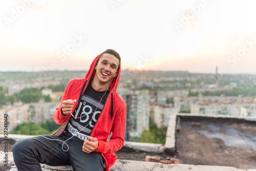 Manly but romantic sport man listening music by headphones at sunset on the background photo