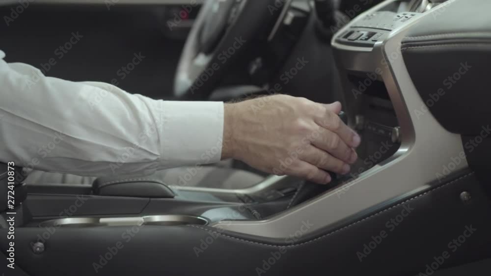 Unrecognized successful man sitting in the vehicle and inspects newly purchased auto from the car dealership. Car showroom. Advertising concept. Unrecognized successful man sitting in the vehicle and inspects newly purchased auto from the car dealership. Car showroom. Advertising concept.