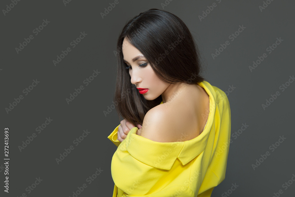 Fashion young woman in yellow clothes. Long luxurious hair and red lipstick. Dark background Fashion young woman in yellow clothes. Long luxurious hair and red lipstick. Dark background