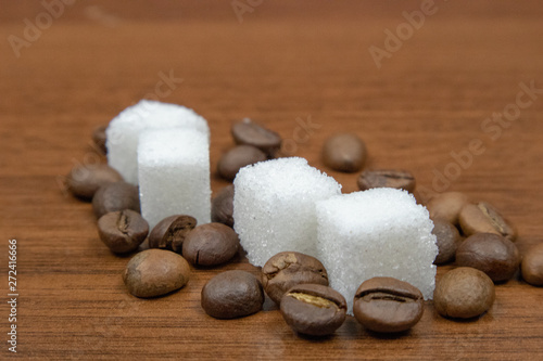 Coffee beans and refined sugar on a wooden table