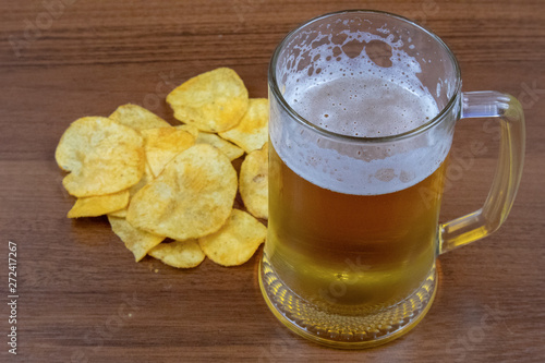 Glass of light beer and chips on a wooden table