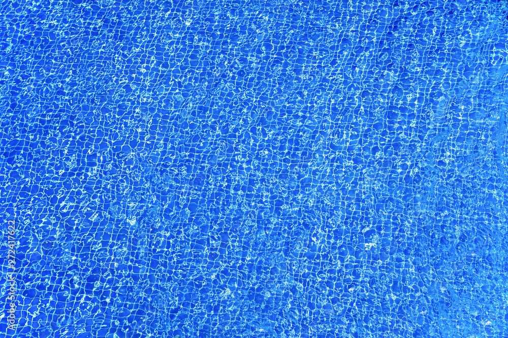 The surface of the water in the pool with blue tiles. Abstract texture background The surface of the water in the pool with blue tiles. Abstract texture background