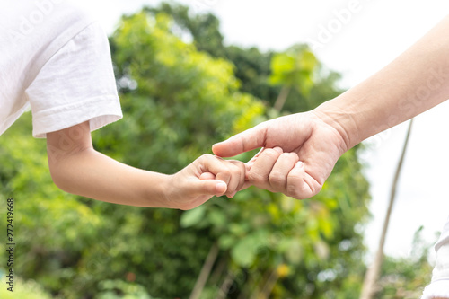 Mother and son holding hand on the background blurred nature. Love concept with parents and family.