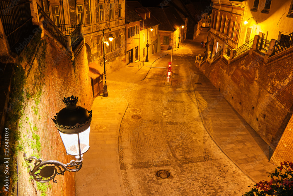 View from Liars Bridge (Podul Minciunilor) in Sibiu, Romania, at night, with beautiful, artistic, medieval-style street lamp and stairs. Popular touristic destination. - obrazy, fototapety, plakaty 