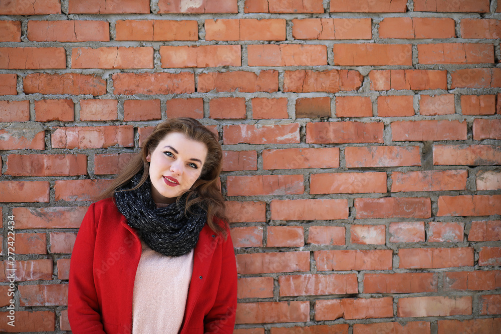Cute girl in red coat on brick wall Cute girl in red coat on brick wall
