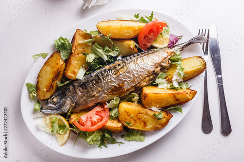 Baked stuffed fish with potatoes on the plate