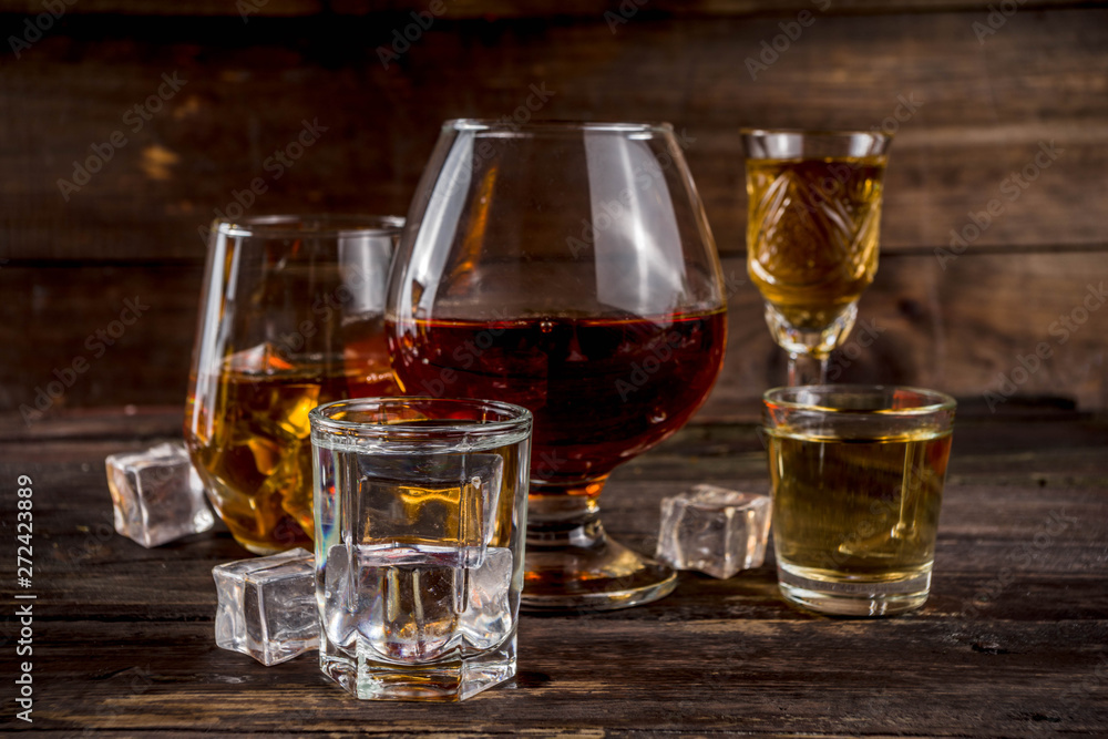 Assortment various hard and strong alcoholic drinks in different glasses: vodka, cognac, tequila, brandy and whiskey, grappa, liqueur, vermouth, tincture, rum, etc. Wooden background copy space Assortment various hard and strong alcoholic drinks in different glasses: vodka, cognac, tequila, brandy and whiskey, grappa, liqueur, vermouth, tincture, rum, etc. Wooden background copy space