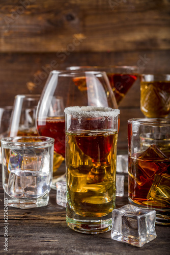 Assortment various hard and strong alcoholic drinks in different glasses: vodka, cognac, tequila, brandy and whiskey, grappa, liqueur, vermouth, tincture, rum, etc. Wooden background copy space