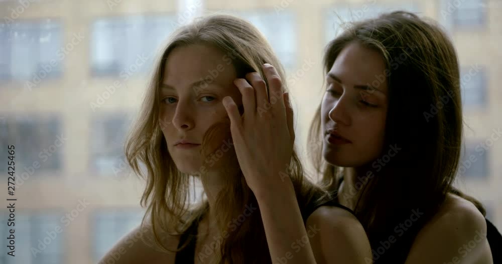 pair of sexual young women are sitting indoors in front large window with urban view pair of sexual young women are sitting indoors in front large window with urban view