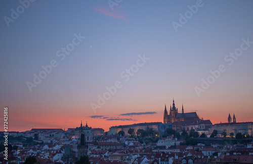 Orange sky sunset behind Prague Castle  with crescent moon in sky