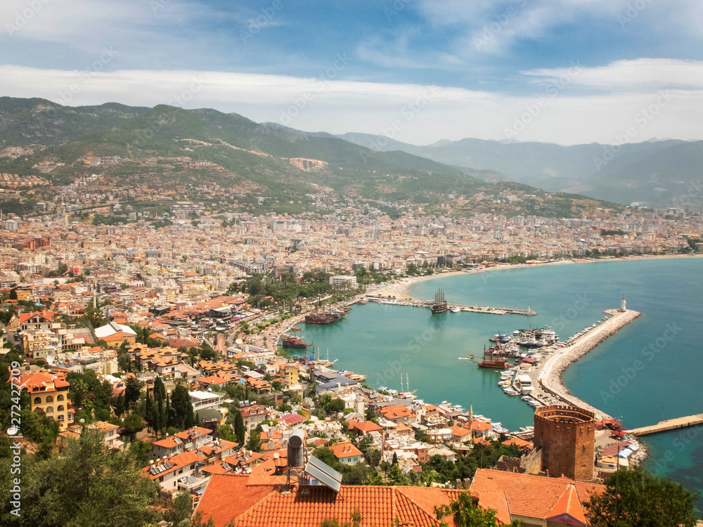Panoramic view of Alanya, nautical vessels in the harbor, Kizil Kule tower and mountains