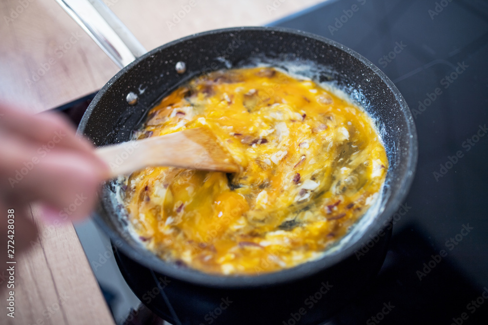 A close-up of cooking scrambled eggs on pan at home. A close-up of cooking scrambled eggs on pan at home.