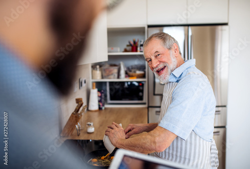 Happy senior man indoors in kitchen at home, cooking.