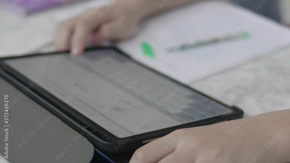 Close up boy hands doing homework using a tablet computer to find information. Close up boy hands doing homework using a tablet computer to find information.