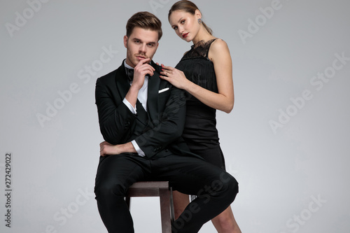 Young groom sitting beside his standing girlfriend
