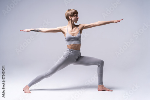 Young attractive Woman practicing home yoga, working out, wearing sportswear. Healthy life, keep fit concepts.