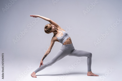 Sporty concentrated woman in sportswear practicing yoga, standing in anjaneyasana pose, attractive girl doing Horse rider exercise, working out at home or in yoga studio