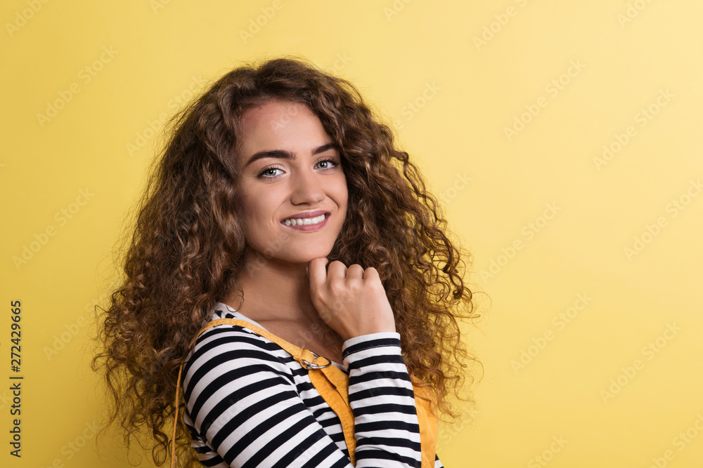 Portrait of a young woman standing in a studio on a yellow background. Portrait of a young woman standing in a studio on a yellow background.