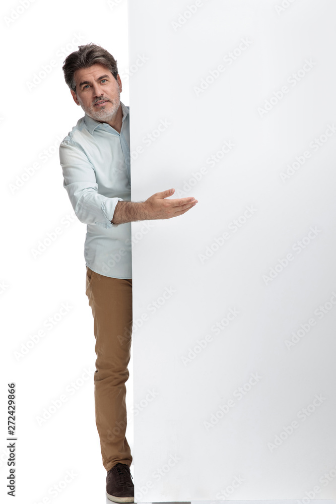 Casual old man presenting something while behind a wall Casual old man presenting something while behind a wall