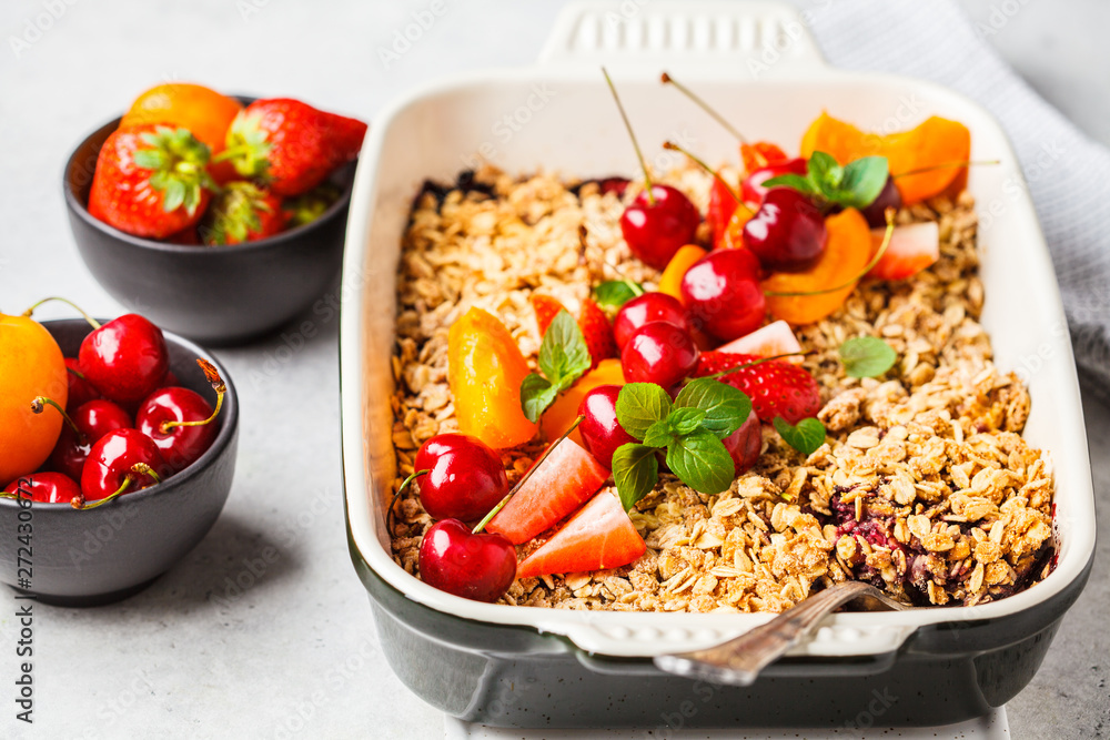 Fruits and berries oat crumble in oven dish on gray background. Fruits and berries oat crumble in oven dish on gray background.