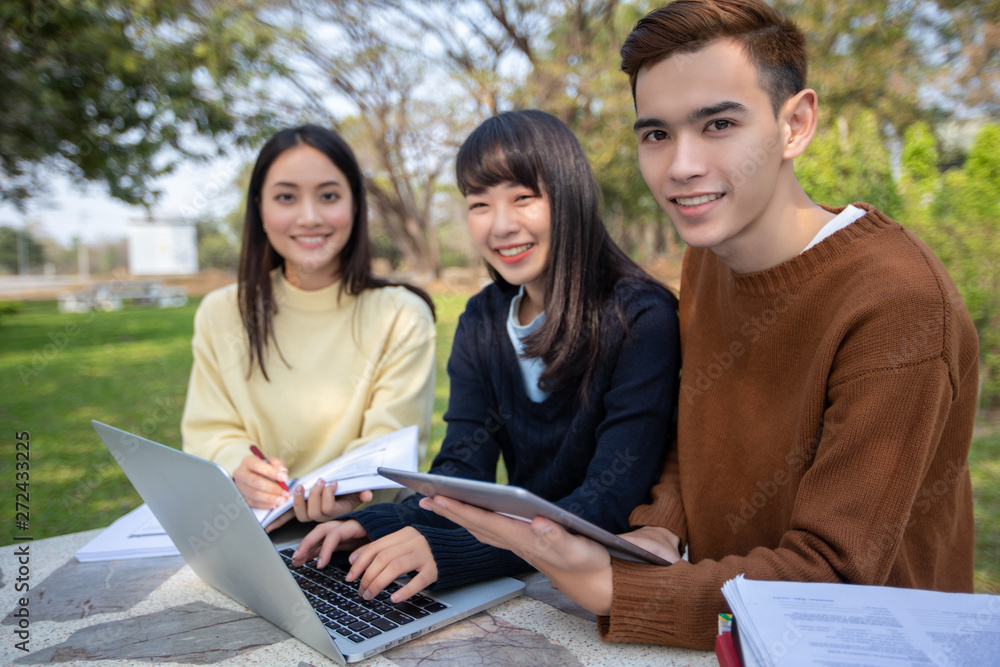 Group Of University Students asian sitting on the green grass Working and reading Outside Together in a park Group Of University Students asian sitting on the green grass Working and reading Outside Together in a park