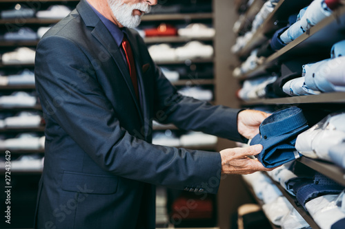 Stylish and modern senior business man choosing and buying shirt in expensive store.