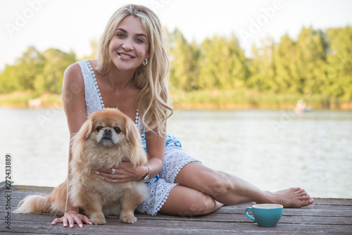 Nice blonde woman with her dog on a lake, concept of love to pets. Friendship human and animals 