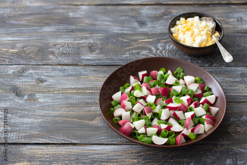 Fresh radish salad with green onions on a wooden background, rustic style